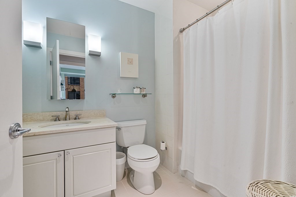 80 Broad Street, Unit 1002 Boston, MA 02110 - Photo 11 of 16 a bathroom with a toilet a sink and a mirror