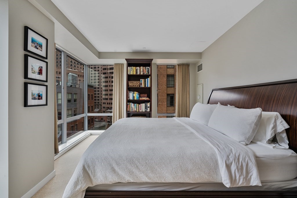80 Broad Street, Unit 1002 Boston, MA 02110 - Photo 7 of 16 a bedroom with a large bed and a book shelf