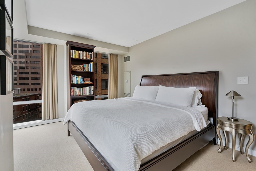 80 Broad Street, Unit 1002 Boston, MA 02110 - Photo 8 of 16 a bedroom with a bed and a book shelf