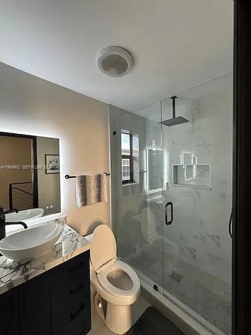 a bathroom with a granite countertop sink toilet and shower