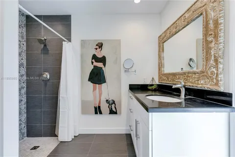 a bathroom with a granite countertop sink a mirror and shower