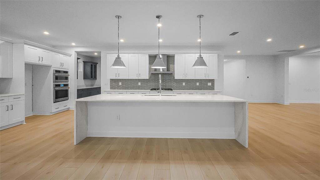 1615 Bellagio Loop Tavares, FL 32778 - Photo 4 of 39 a large kitchen with stainless steel appliances kitchen island a large counter top and a refrigerator