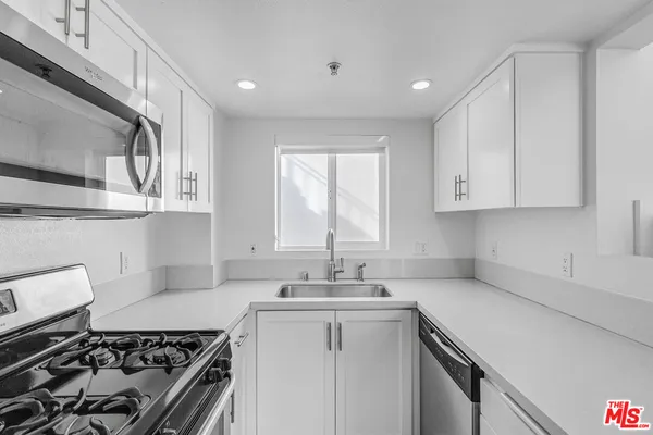 a kitchen with a sink stove top oven and cabinets