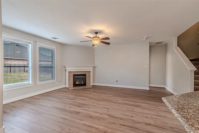 a view of a livingroom with a fireplace a ceiling fan and windows