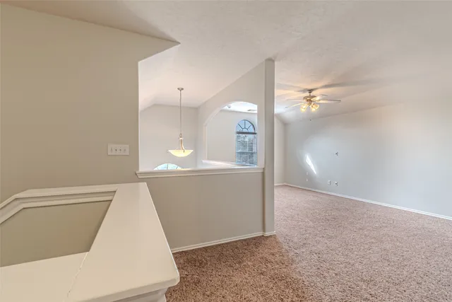 a view of an empty room with chandelier fan