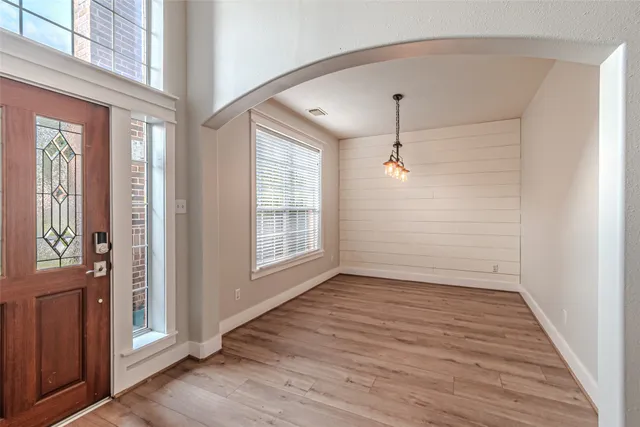 a view of an empty room with a window and wooden floor