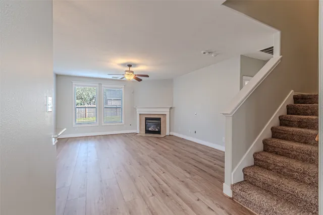 a view of an empty room with wooden floor fireplace and a window