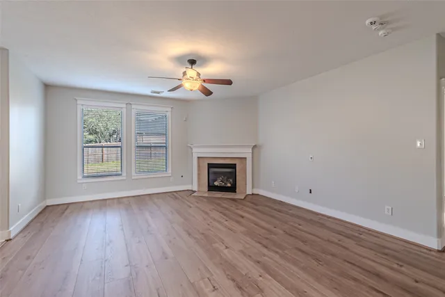 a view of an empty room with a window and wooden floor