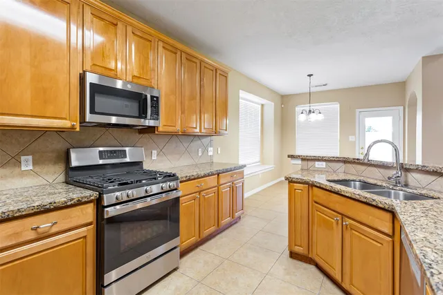 a kitchen with stainless steel appliances granite countertop a sink stove and microwave