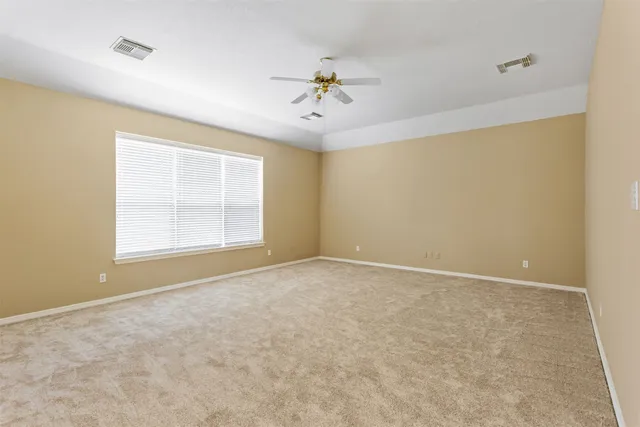an empty room with windows and ceiling fan