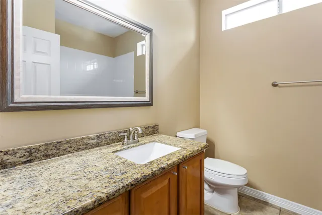 a bathroom with a granite countertop sink toilet and mirror