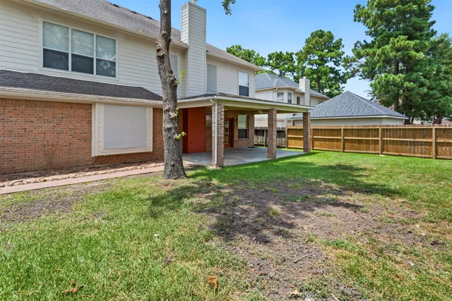 a view of a house with a yard and large tree
