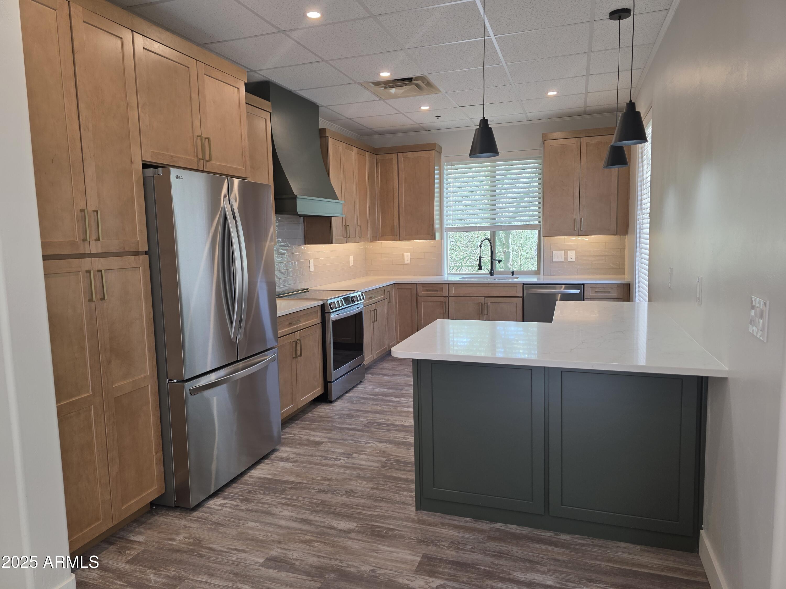 a kitchen with stainless steel appliances granite countertop a refrigerator a sink and a stove