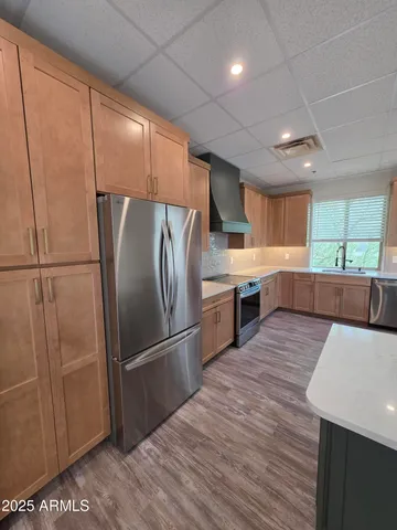 a kitchen with stainless steel appliances a refrigerator sink and wooden cabinets