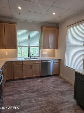 a large kitchen with stainless steel appliances granite countertop a sink a window and wooden floor