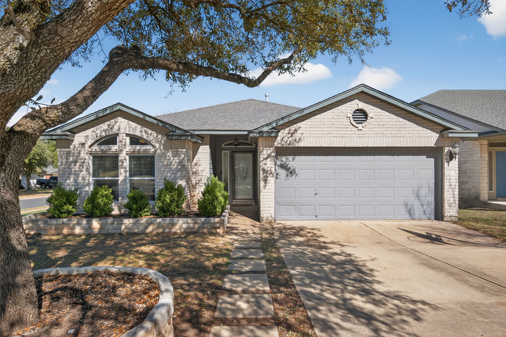 Ranch-style home with driveway, an attached garage, brick siding, and a shingled roof