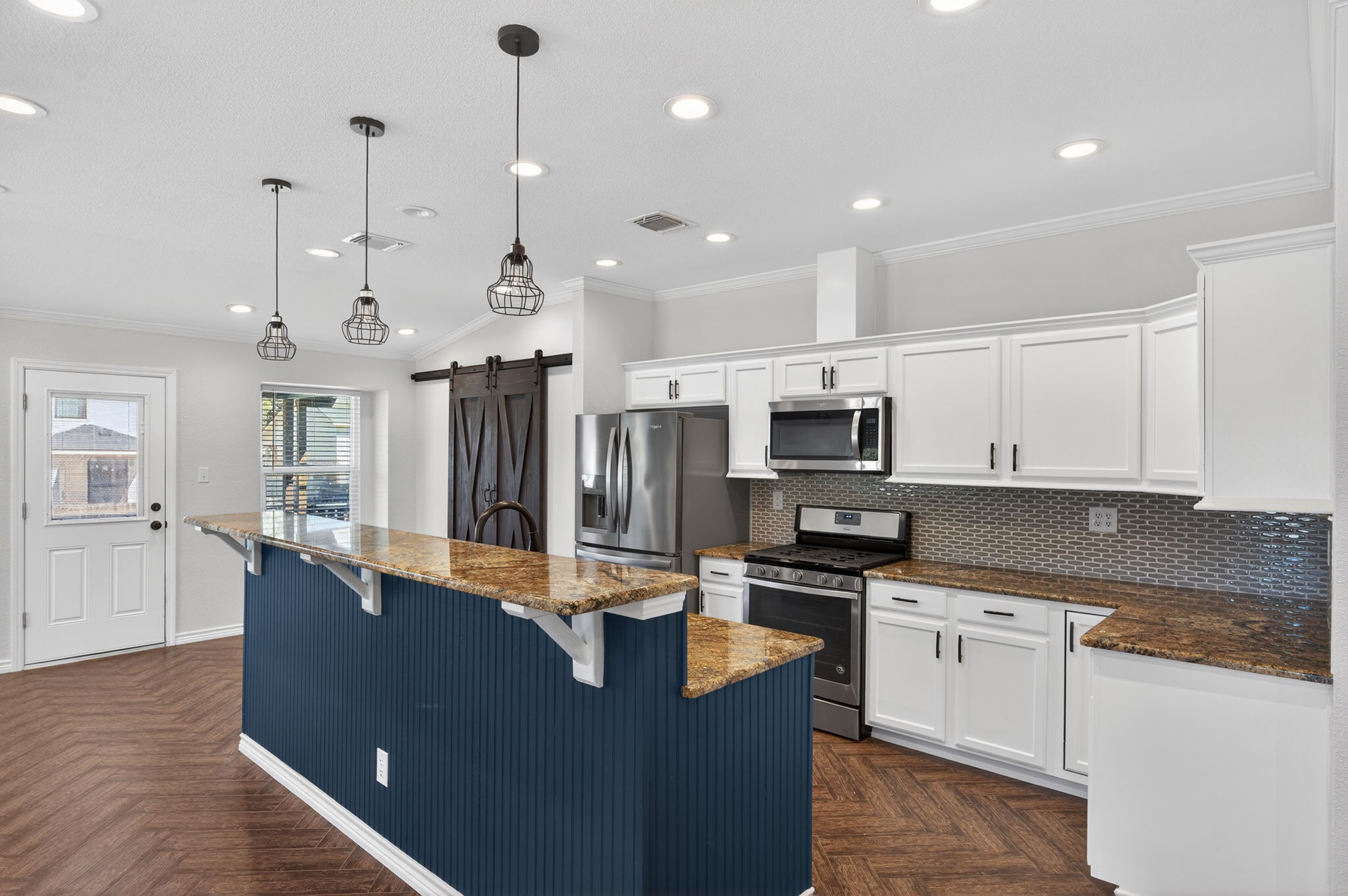 1201 Dillon Lake Bend Leander, TX 78641 - Photo 9 of 38 Kitchen featuring a barn door, stainless steel appliances, dark stone counters, white cabinets, and ornamental molding