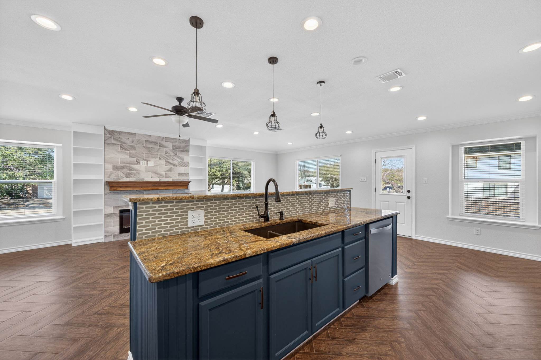 1201 Dillon Lake Bend Leander, TX 78641 - Photo 13 of 38 Kitchen featuring light stone counters, blue cabinets, a center island with sink, a tiled fireplace, and parquet floors