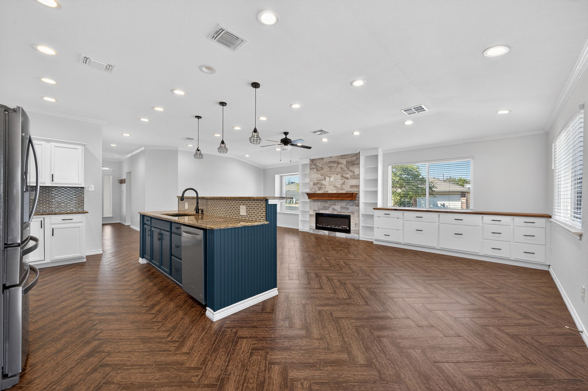 1201 Dillon Lake Bend Leander, TX 78641 - Photo 38 of 38 Kitchen featuring two tone cabinets, a fireplace, open floor plan, pendant lighting, and crown molding