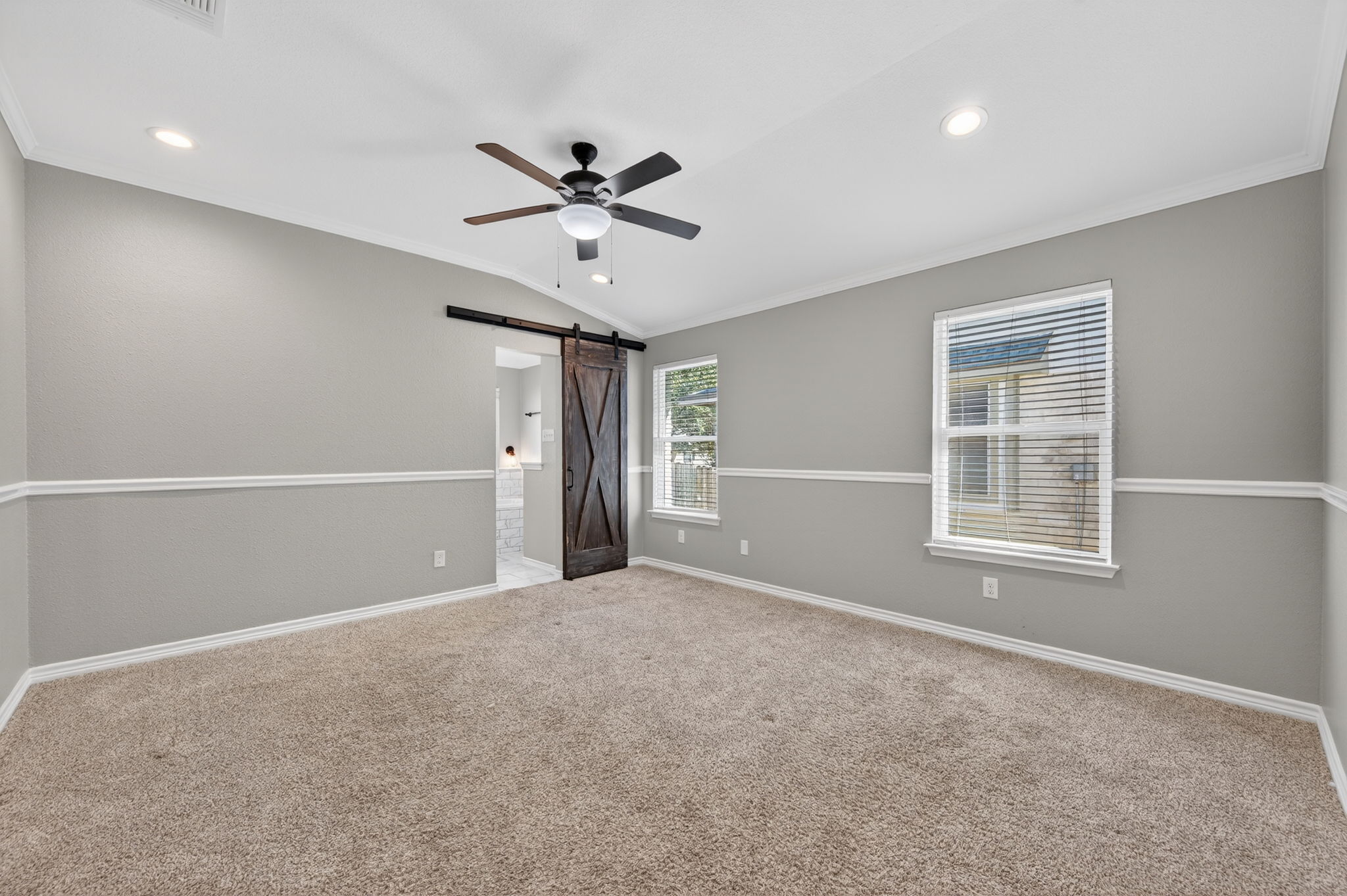 1201 Dillon Lake Bend Leander, TX 78641 - Photo 16 of 38 Primary bedroom featuring lofted ceiling, a barn door, crown molding, ceiling fan, and recessed lighting