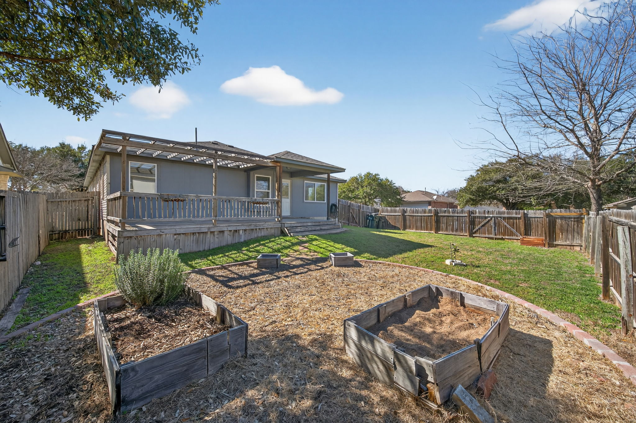 1201 Dillon Lake Bend Leander, TX 78641 - Photo 34 of 38 Rear view of house featuring a vegetable garden, a fenced backyard, and a deck