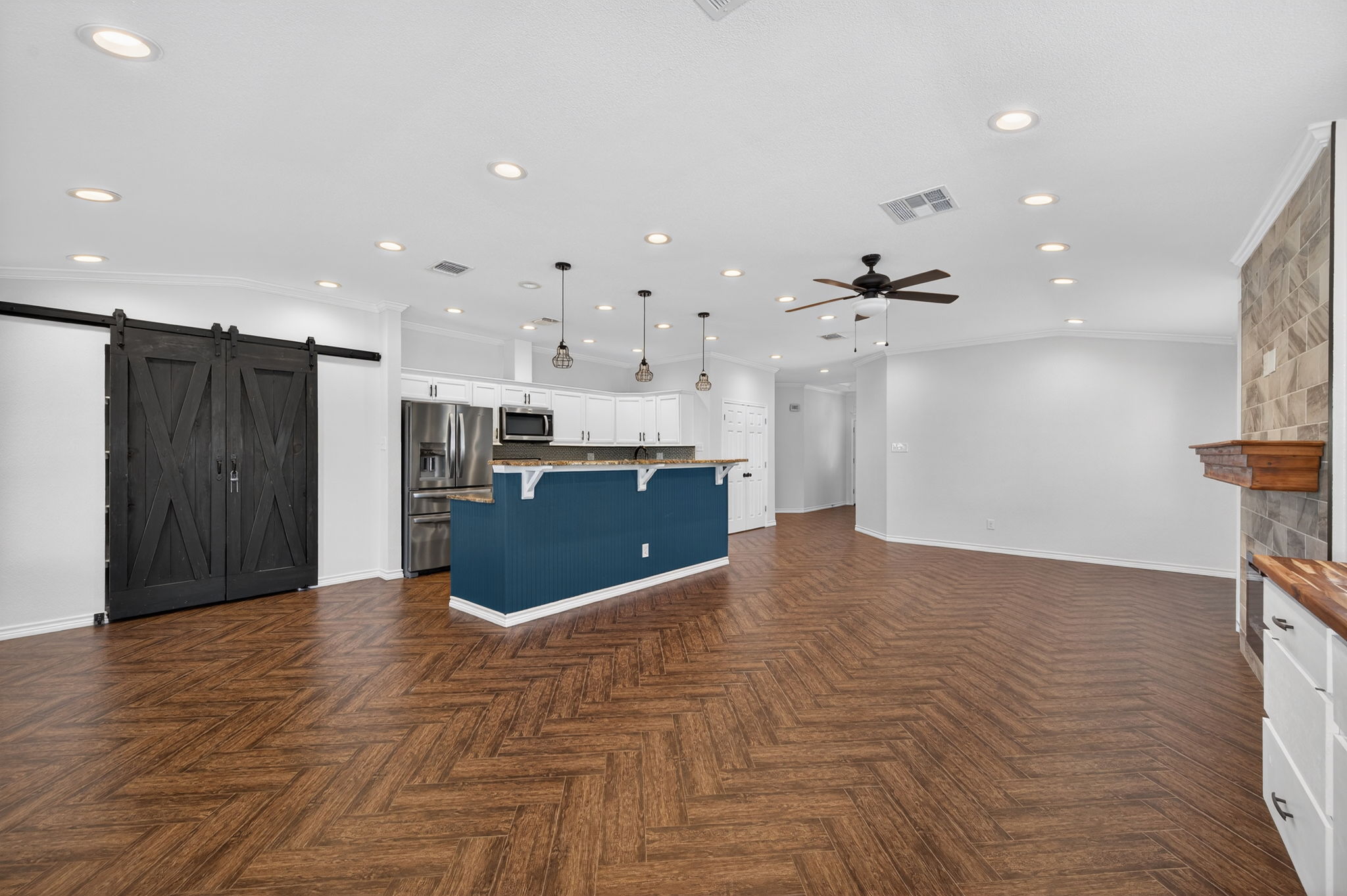 1201 Dillon Lake Bend Leander, TX 78641 - Photo 37 of 38 Kitchen with a barn door, stainless steel appliances, white cabinets, open floor plan, and hanging light fixtures