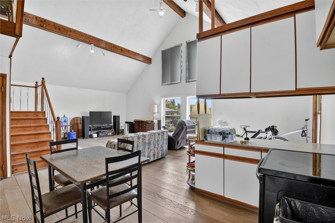 1526 Stevenson Road Ashtabula, OH 44004 - Photo 14 of 50 Open-concept living area featuring vaulted ceilings with exposed wood beams, wood-finish flooring, and a prominent staircase with wood treads and metal balusters