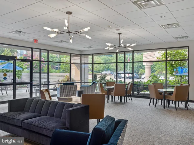 a living room with furniture a chandelier fan and a large window