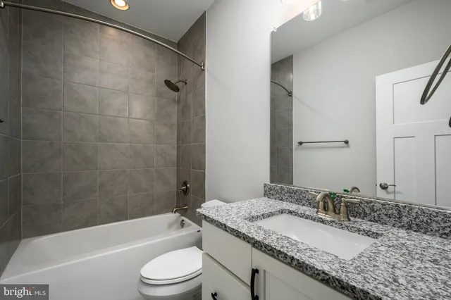 a bathroom with a granite countertop sink toilet bathtub and shower