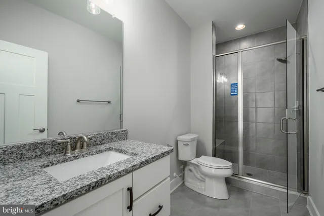 a bathroom with a granite countertop sink a toilet and shower