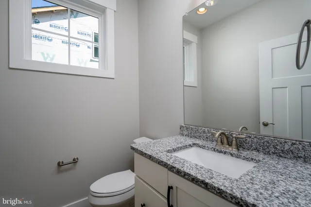 a bathroom with a granite countertop sink toilet a mirror and window