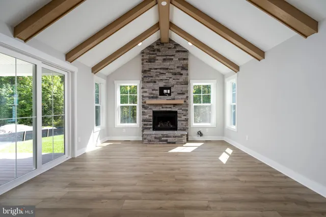 a view of a livingroom with wooden floor a fireplace and windows