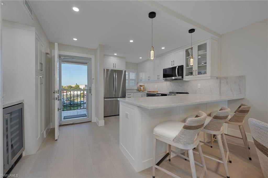 57 High Point Circle West, Unit 405 Naples, FL 34103 - Photo 3 of 15 a kitchen with kitchen island stainless steel appliances a sink and a refrigerator