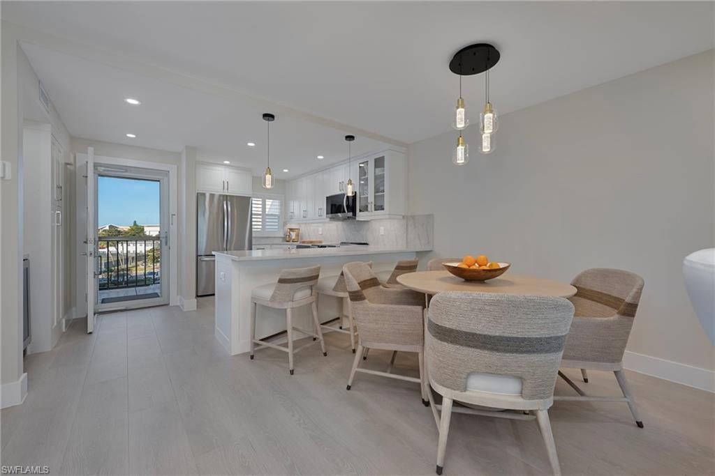 57 High Point Circle West, Unit 405 Naples, FL 34103 - Photo 7 of 15 a kitchen with a dining table chairs and white cabinets