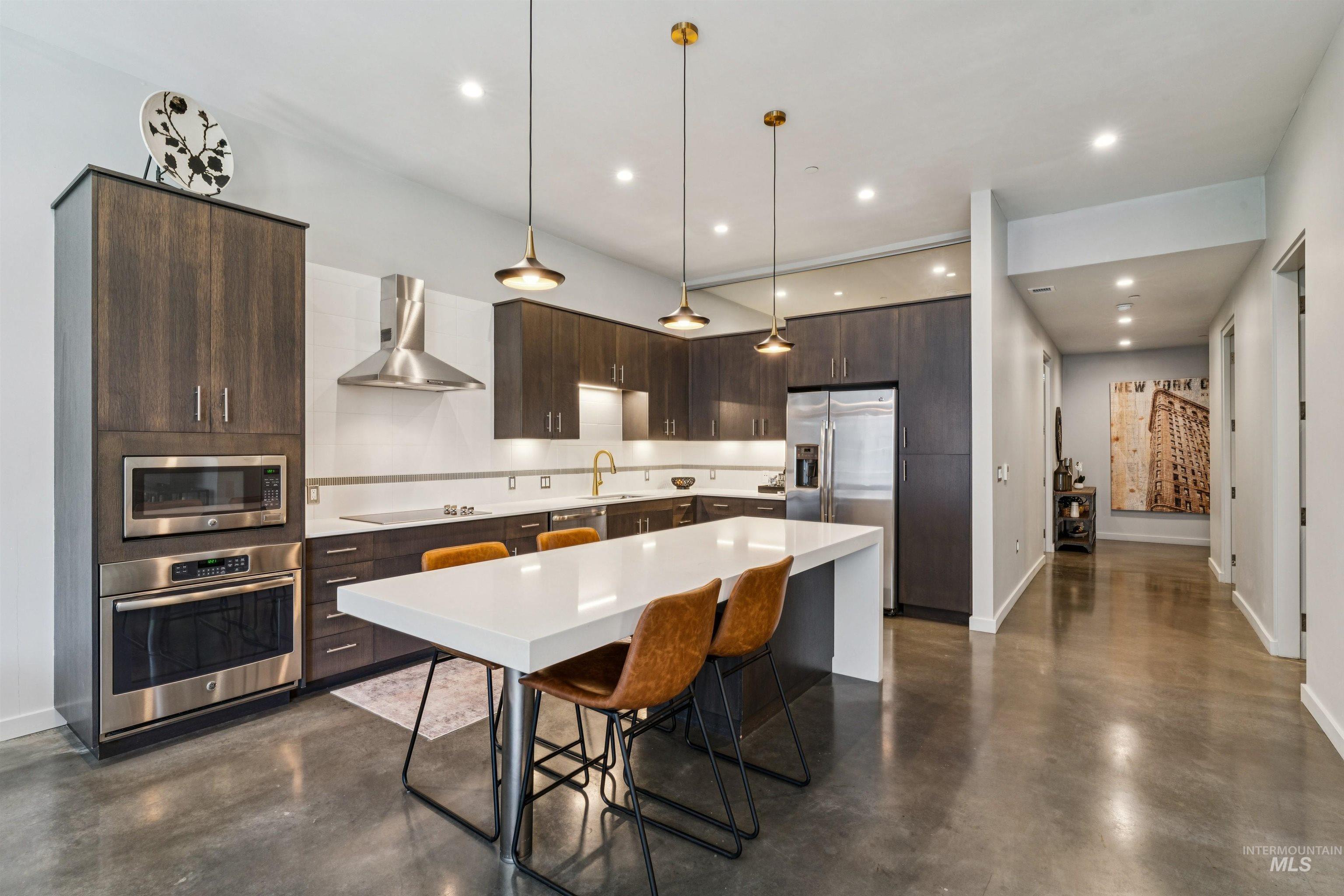119 South 10th Street, Unit 307 Boise, ID 83702 - Photo 6 of 47 Modern kitchen featuring dark wood-finish cabinetry, stainless steel appliances, a white island countertop, recessed lighting, and pendant fixtures