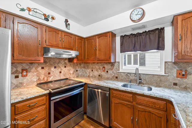 a kitchen with stainless steel appliances granite countertop a sink dishwasher stove and cabinets with wooden floor