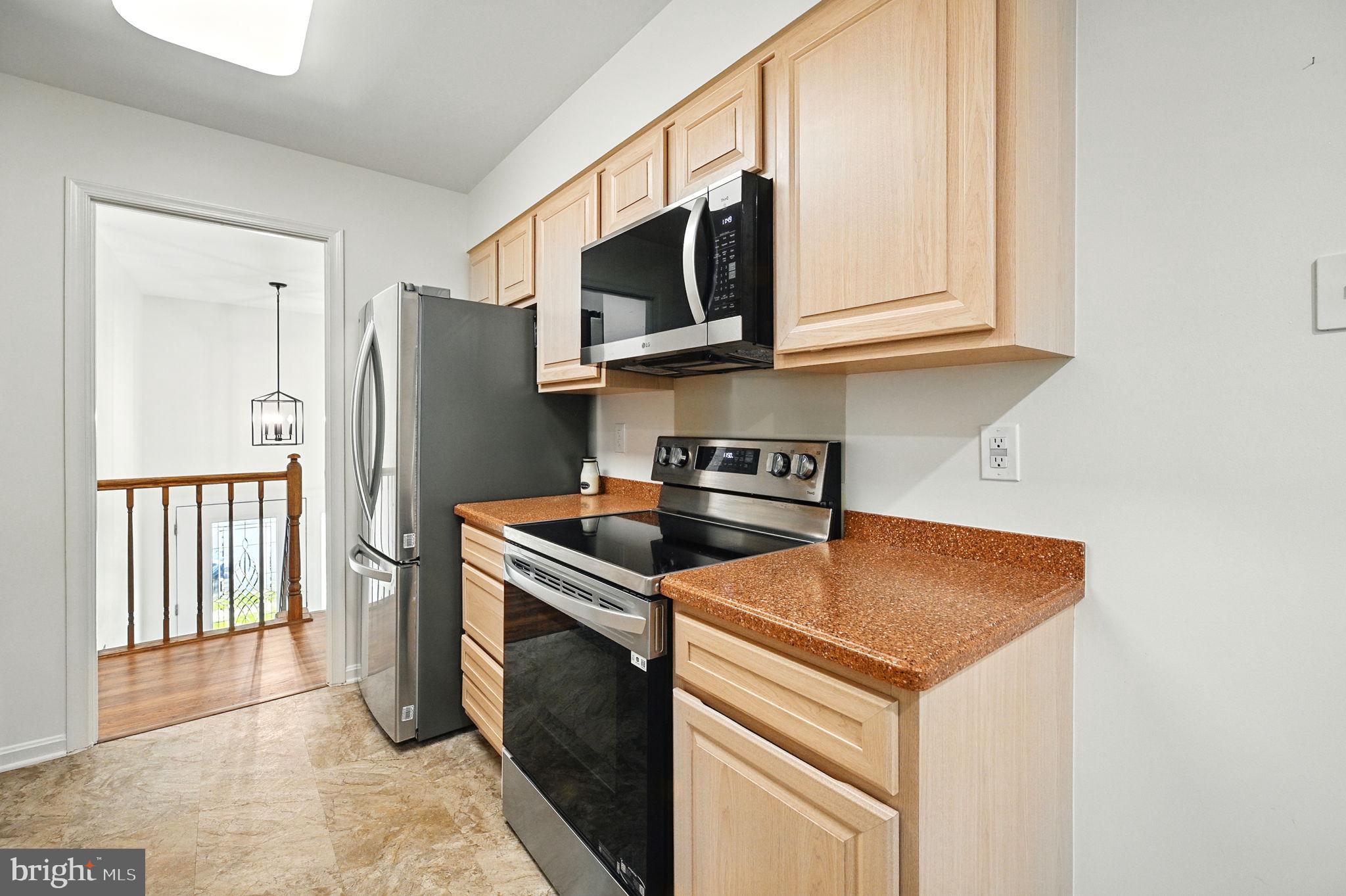 8923 Renshaw Court Springfield, VA 22153 - Photo 21 of 38 a kitchen with stainless steel appliances granite countertop a stove a microwave and a refrigerator