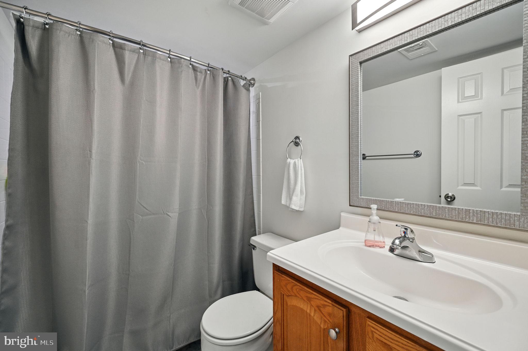 8923 Renshaw Court Springfield, VA 22153 - Photo 9 of 38 a bathroom with a sink a toilet a mirror and shower curtain
