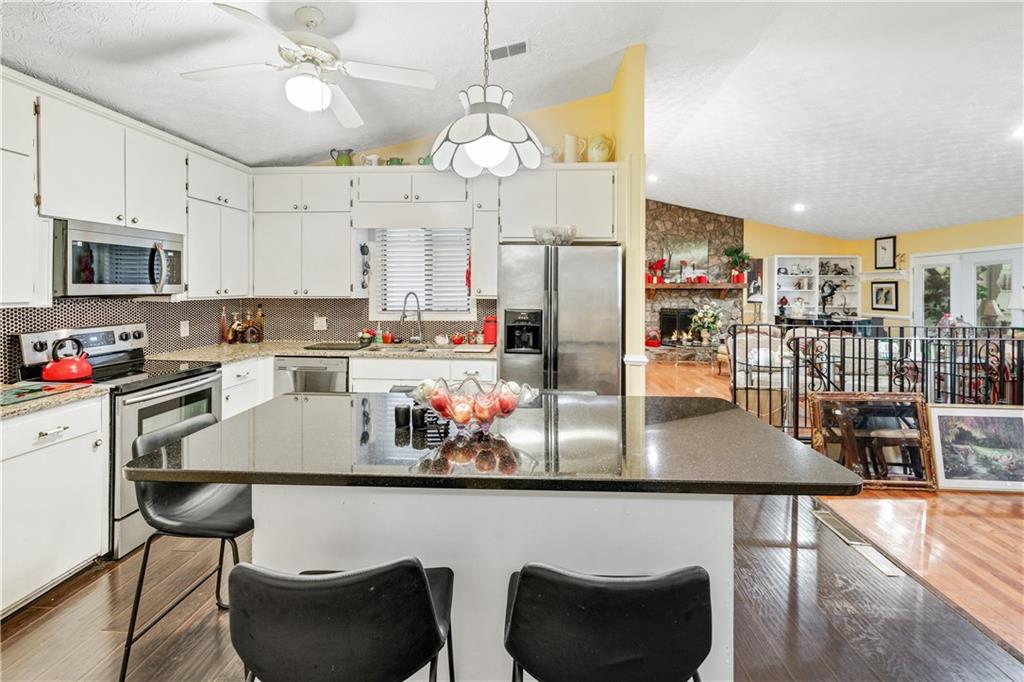 3960 Highway 20 Conyers, GA 30013 - Photo 10 of 57 a kitchen with stainless steel appliances granite countertop a stove top oven a refrigerator a dining table and chairs with wooden floor