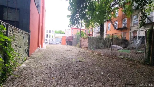 a view of a backyard with large trees and wooden fence