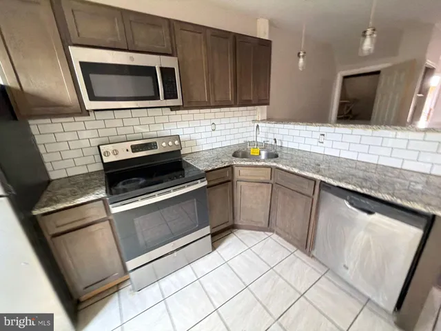 a kitchen with stainless steel appliances kitchen island granite countertop a sink stove and microwave