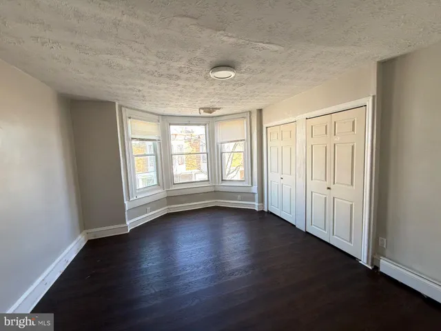 an empty room with wooden floor and windows with curtains