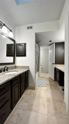 a spacious bathroom with a granite countertop sink and a mirror