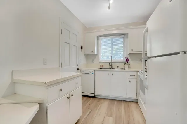 a kitchen with white cabinets and white appliances
