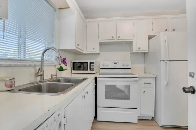 a kitchen with white cabinets and white appliances