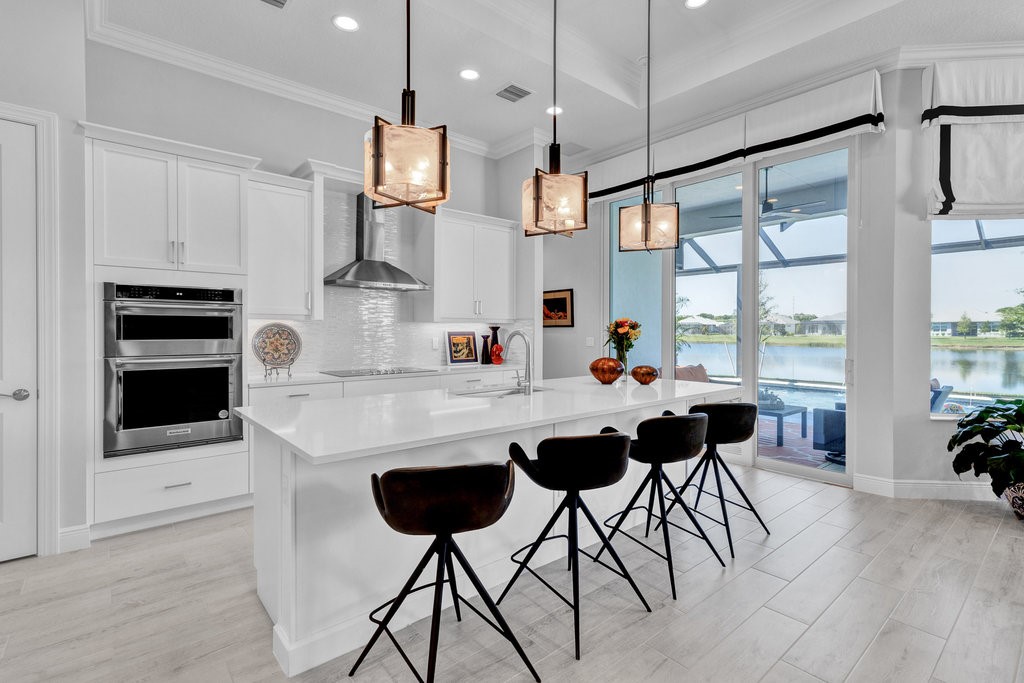 5594 Bent Pine Square Vero Beach, FL 32967 - Photo 13 of 35 a kitchen with stainless steel appliances kitchen island granite countertop a table chairs and a refrigerator