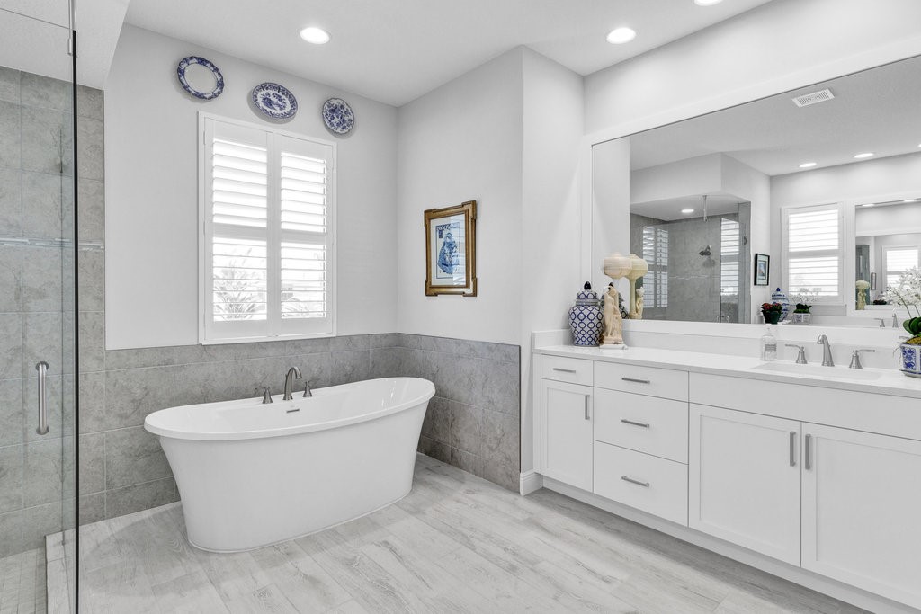 5594 Bent Pine Square Vero Beach, FL 32967 - Photo 18 of 35 a bathroom with a double vanity sink a mirror and a bathtub
