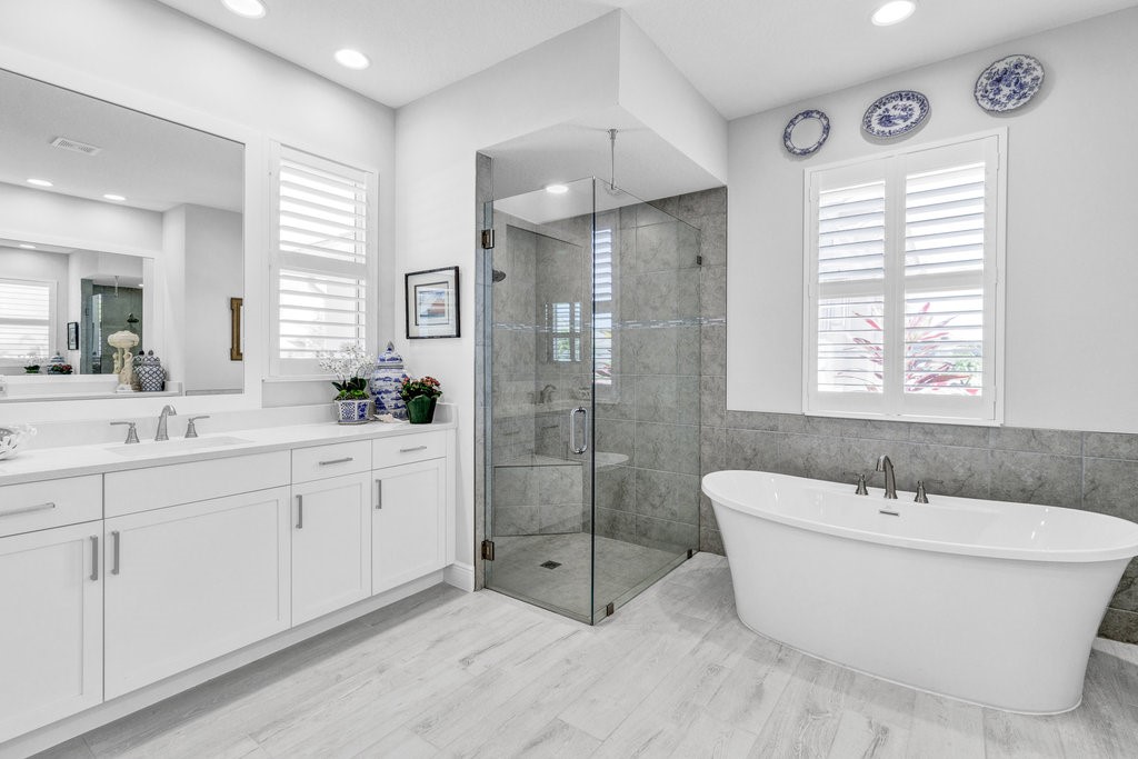 5594 Bent Pine Square Vero Beach, FL 32967 - Photo 19 of 35 a bathroom with a white tub shower sink and mirror