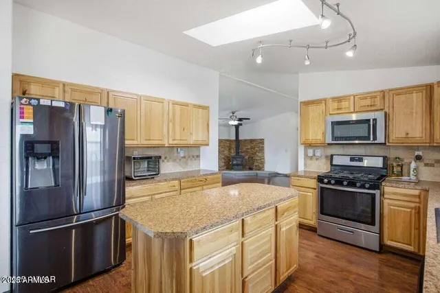 a kitchen with granite countertop a refrigerator stove and microwave