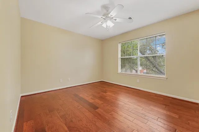 an empty room with windows and ceiling fan
